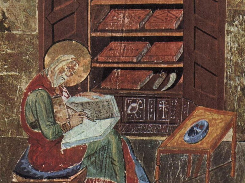 Iluminura: um escriba idoso, com auréola, escreve num livro apoiado nos joelhos; atrás dele, um armário aberto com livros encadernados em vermelho